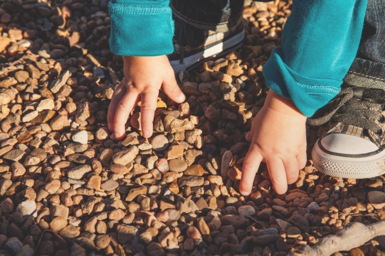 Applied Life Change Facilitation: kid reaching down and touching pebbles